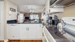 A modern kitchen with white cabinets, a stainless steel stove, and a dishwasher. - Waterfront Condo With Community Pools & hot tub - Walk to the Beach (St. Augustine)