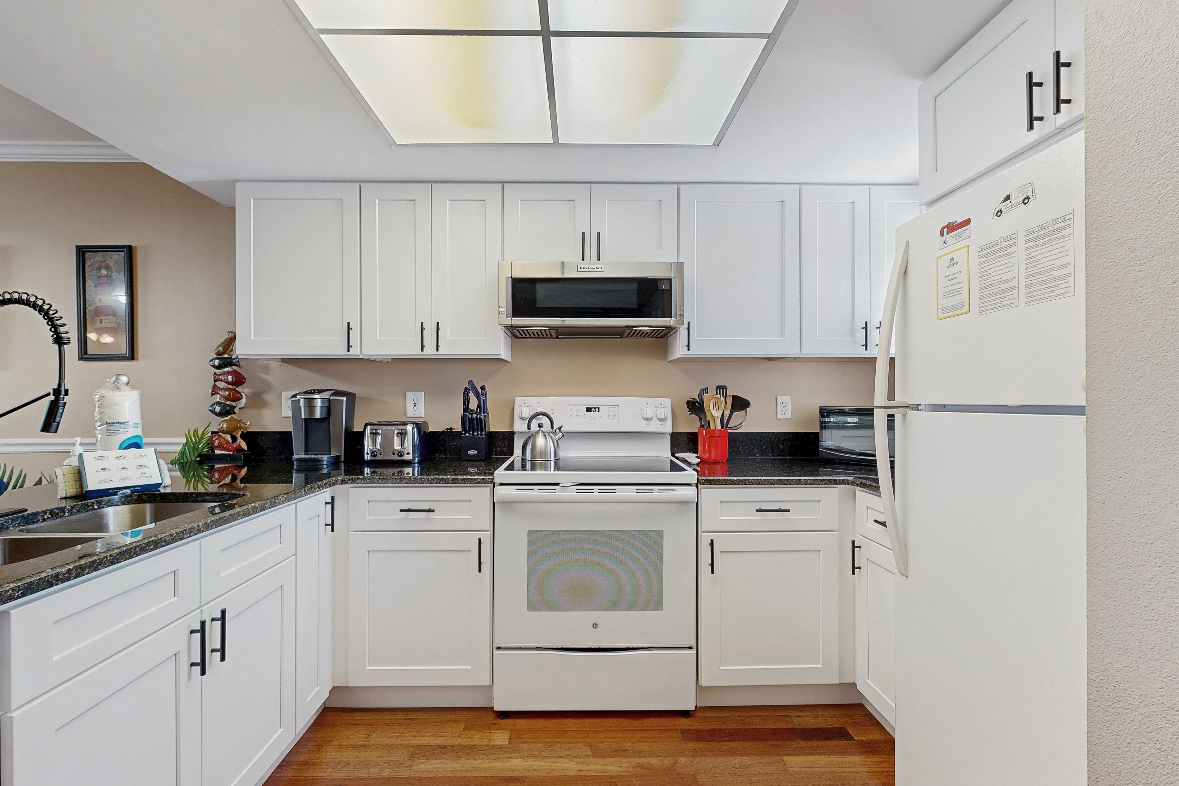 Una cocina moderna con armarios blancos, microondas integrado, estufa y refrigerador.