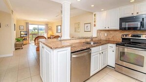A modern kitchen with white cabinets, granite countertops, stainless steel appliances, and a view to the outside. - Updated Oceanfront, Oceanviews! 5 Hot Tubs 2 Resort Pools! Trolley St Augustine Beach (St. Augustine)