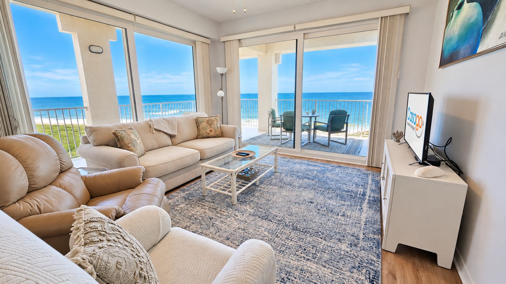 A spacious living room with a large sofa, a coffee table, and a view of the ocean through large windows.
