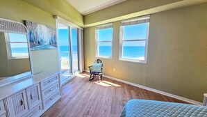 A bedroom with a view of the ocean, a rocking chair, a dresser, and a bed. - Surfclub Retreat 6th Floor Penthouse Corner! Wraparound Balcony! Ocean Views! (Palm Coast)