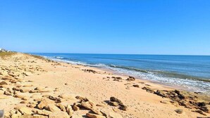 A sandy beach with scattered rocks and a clear blue sky. - Surfclub Retreat 6th Floor Penthouse Corner! Wraparound Balcony! Ocean Views! (Palm Coast)