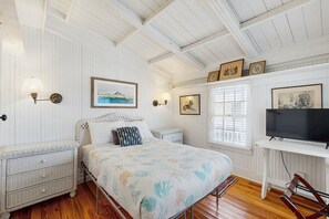 Una camera da letto con un letto, comodini, un mobile TV e quadri appesi al muro.