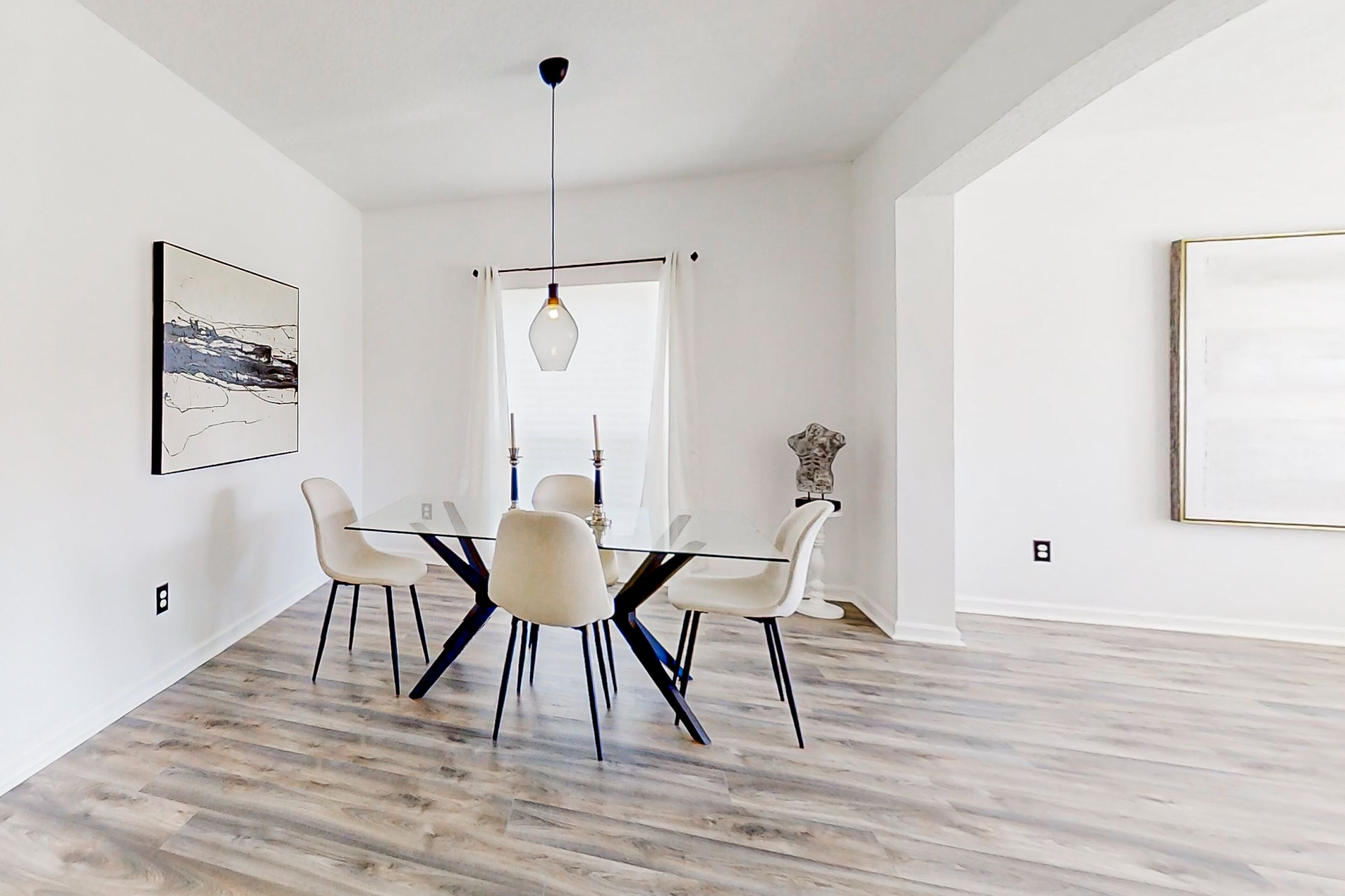 Un espace repas avec une table ronde, des chaises blanches et un luminaire suspendu.