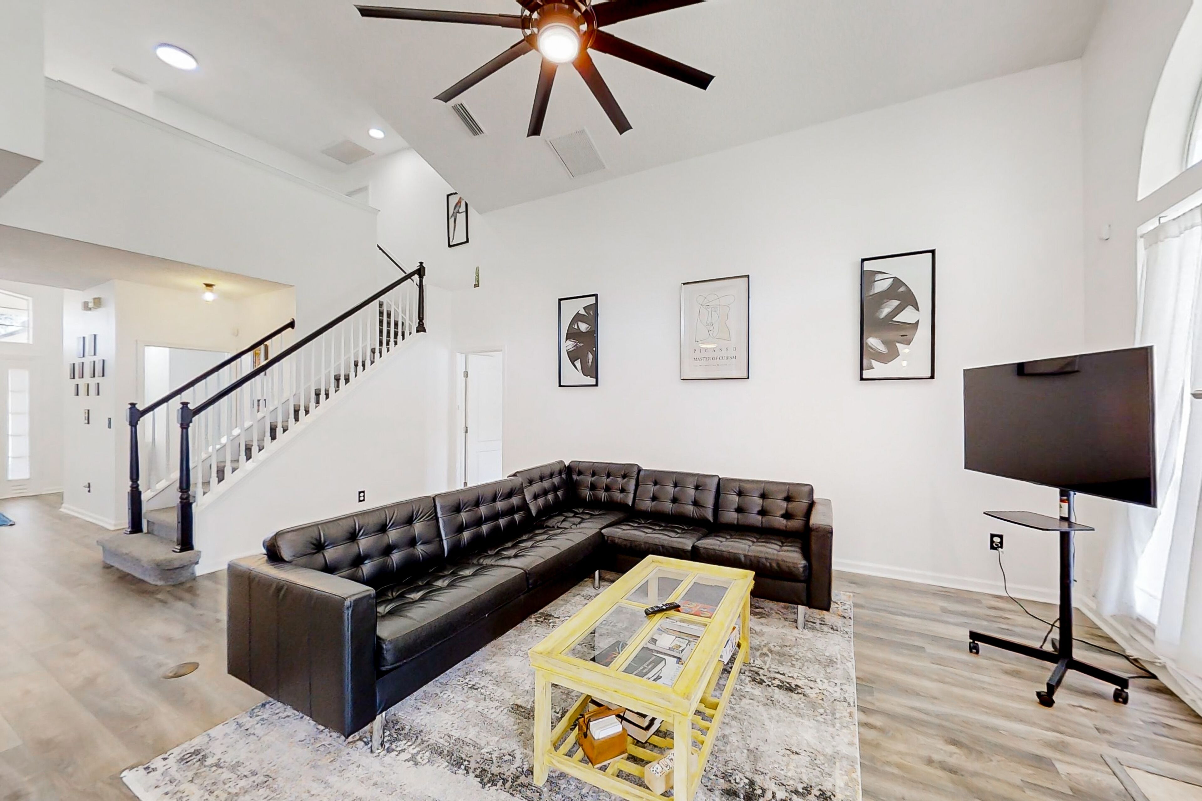 A spacious living room with a sectional sofa, a glass coffee table, and a flat-screen TV.