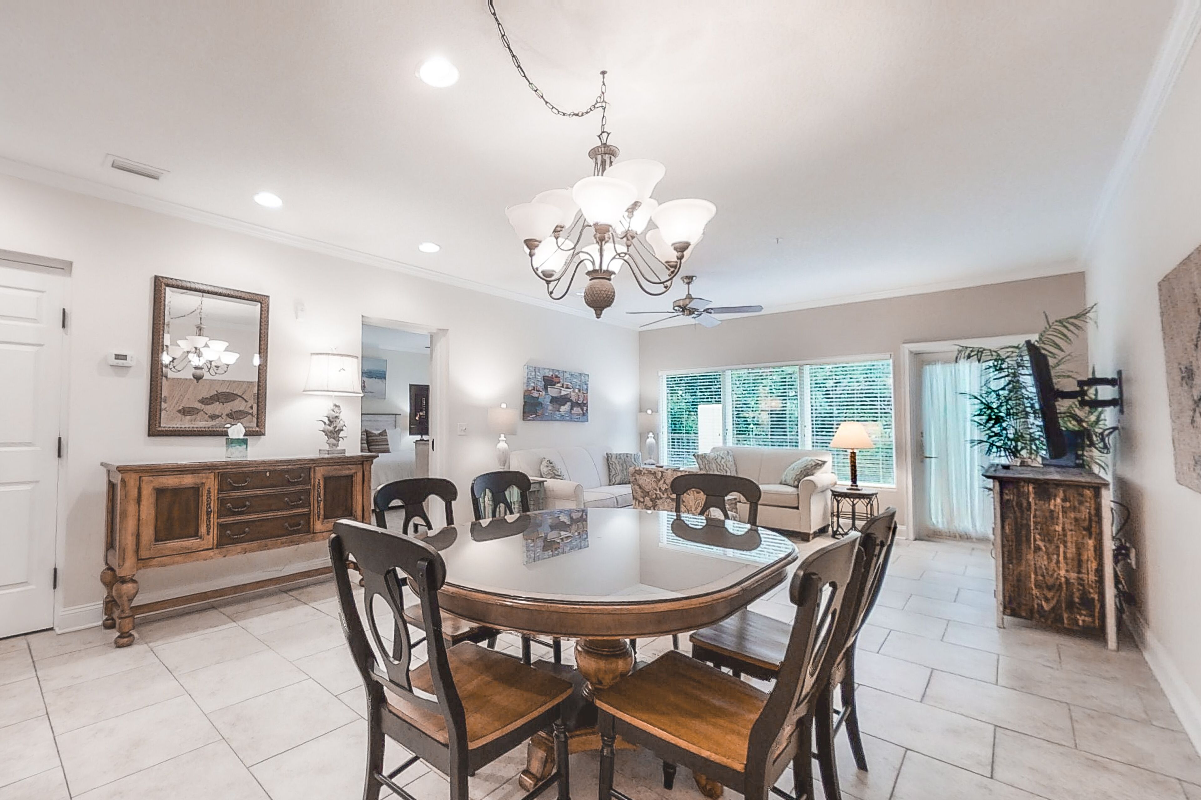 A spacious dining area with a round table, wooden chairs, and a chandelier.