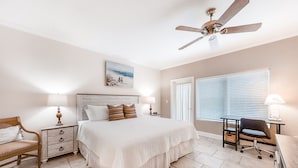 A bedroom with a bed, a desk, a chair, a nightstand, a lamp, a ceiling fan, and a window with blinds. - Wonderful Home Close to Beach W/shared Pool, Free Wifi, Central AC, W/D (Fernandina Beach)