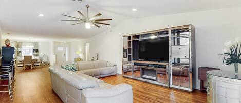 A modern living room with a sectional sofa, a TV, and a glass cabinet.