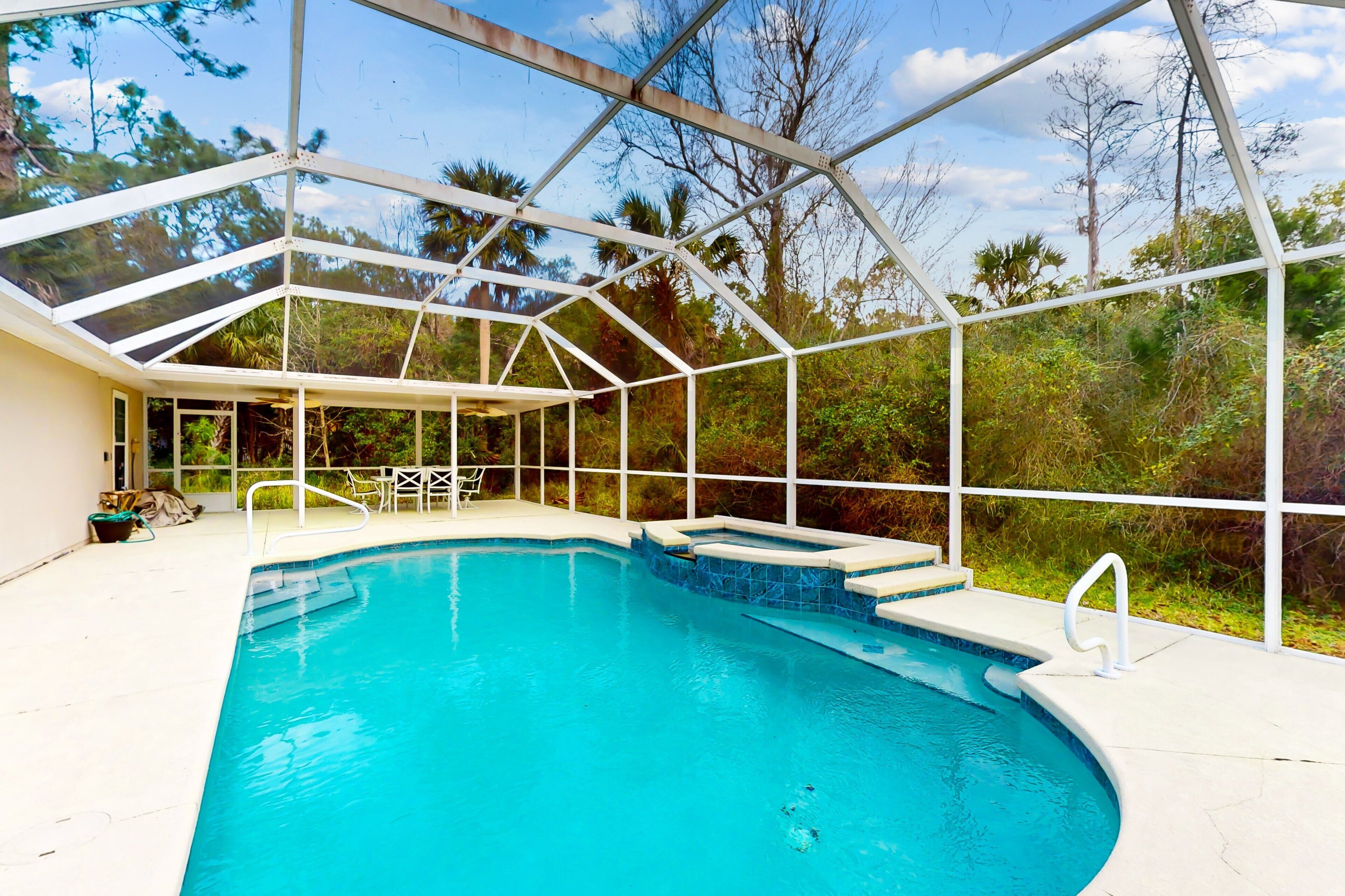 A swimming pool with a glass enclosure, surrounded by greenery.