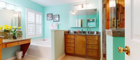 A modern bathroom with a large mirror, a bathtub, and wooden cabinets.