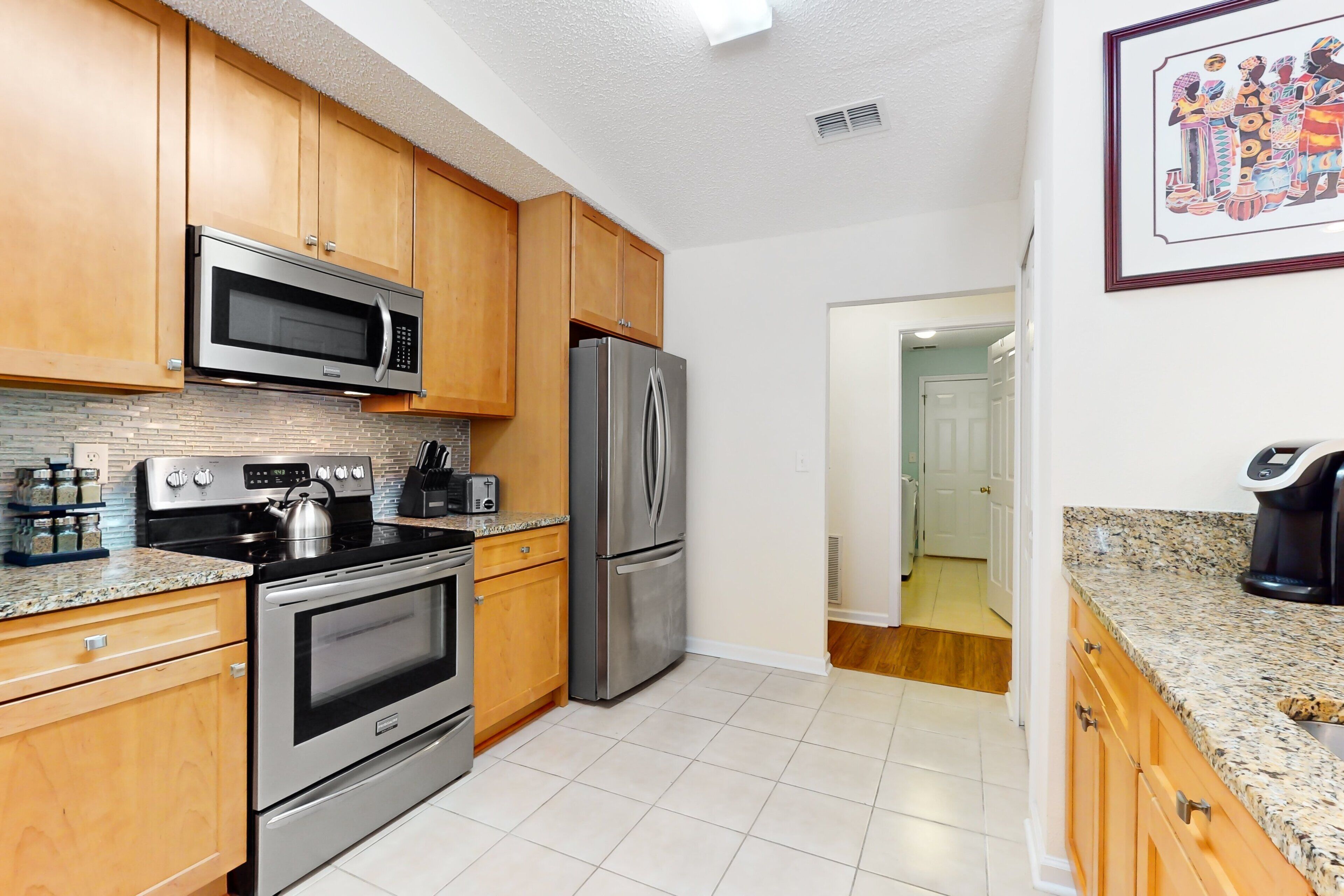 A kitchen with wooden cabinets, stainless steel appliances, granite countertops, and a tiled floor.
