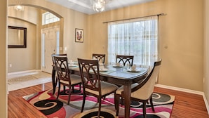 A dining area with a wooden table, chairs, and a chandelier. - Wonderful Coastal Home With Wifi, Enclosed Backyard, Screened Patio (Palm Coast)