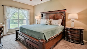 A bedroom with a wooden bed, two bedside lamps, a nightstand, and a ceiling fan. - Wonderful Coastal Home With Wifi, Enclosed Backyard, Screened Patio (Palm Coast)
