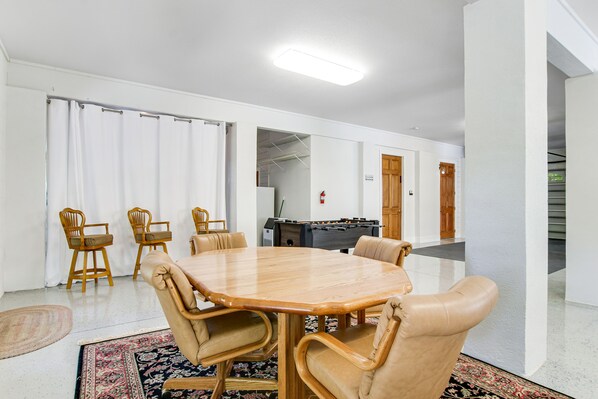 A conference room with a wooden table and leather chairs, a foosball table, and a visible fire extinguisher. - Welcoming Home With Golf Course View, High-speed Wifi, and Central AC (St. Simons Island)