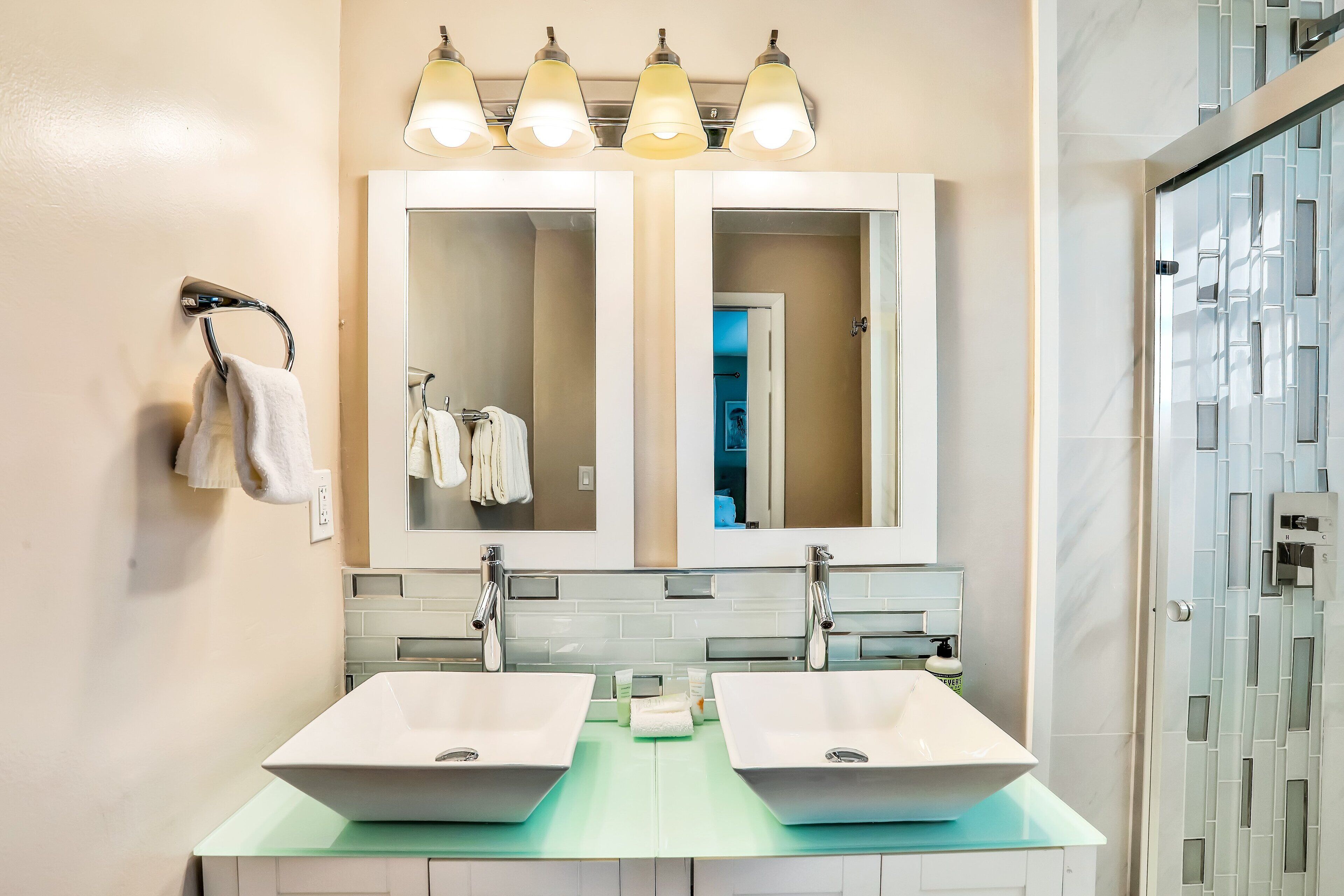 Une salle de bain avec deux lavabos, un grand miroir et un porte-serviettes.