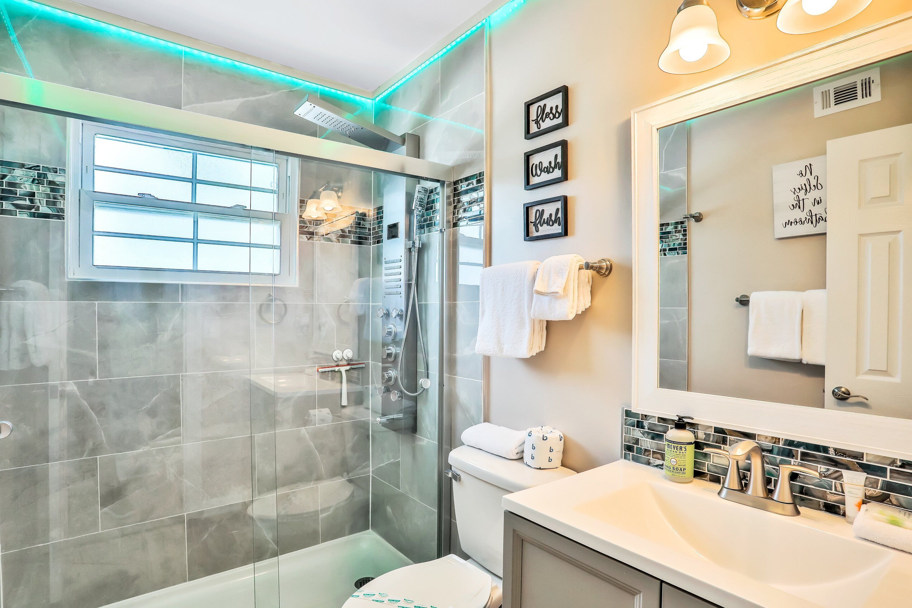 A modern bathroom with a glass shower enclosure, a white sink, and a large mirror.