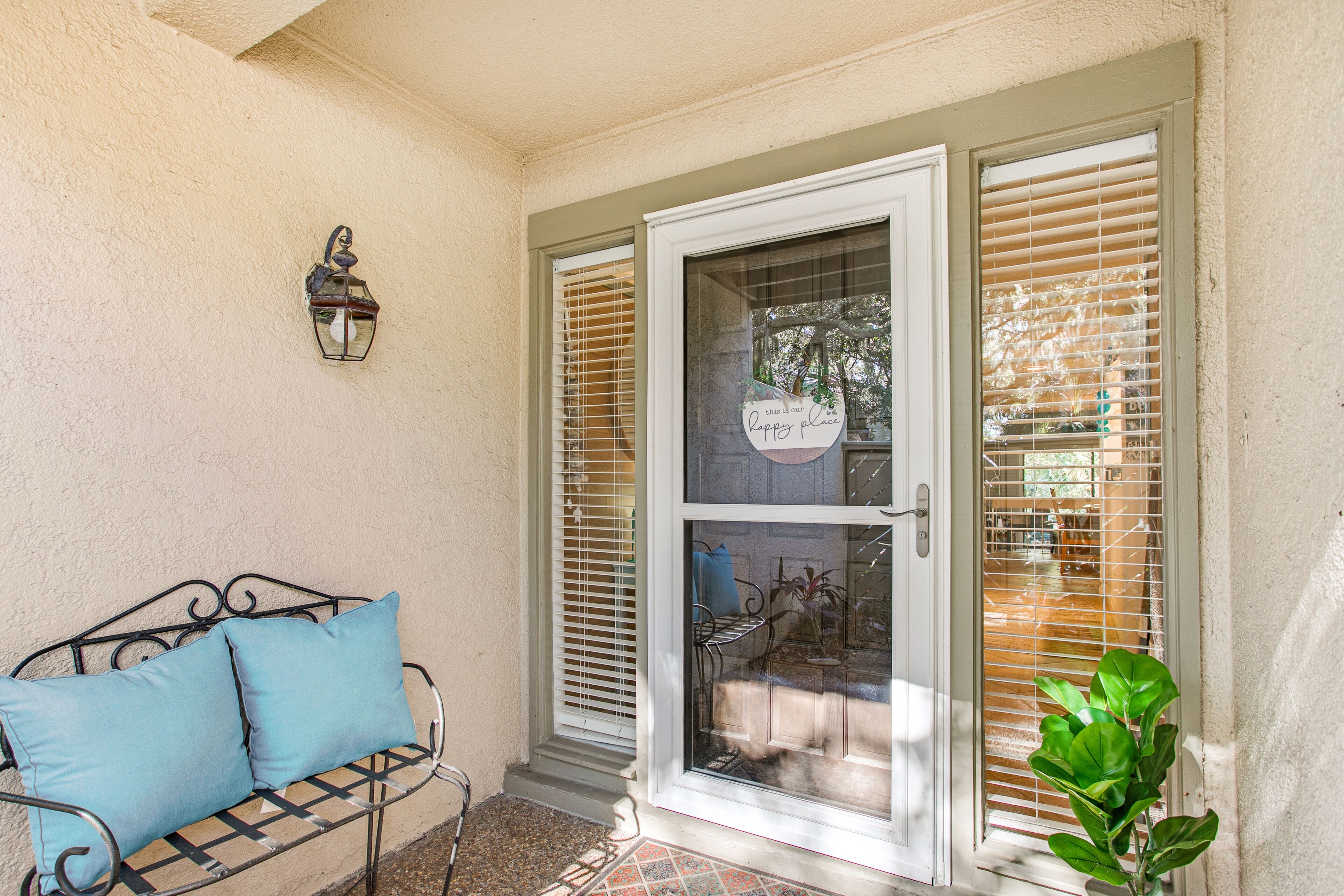 A covered porch with a bench and a potted plant.