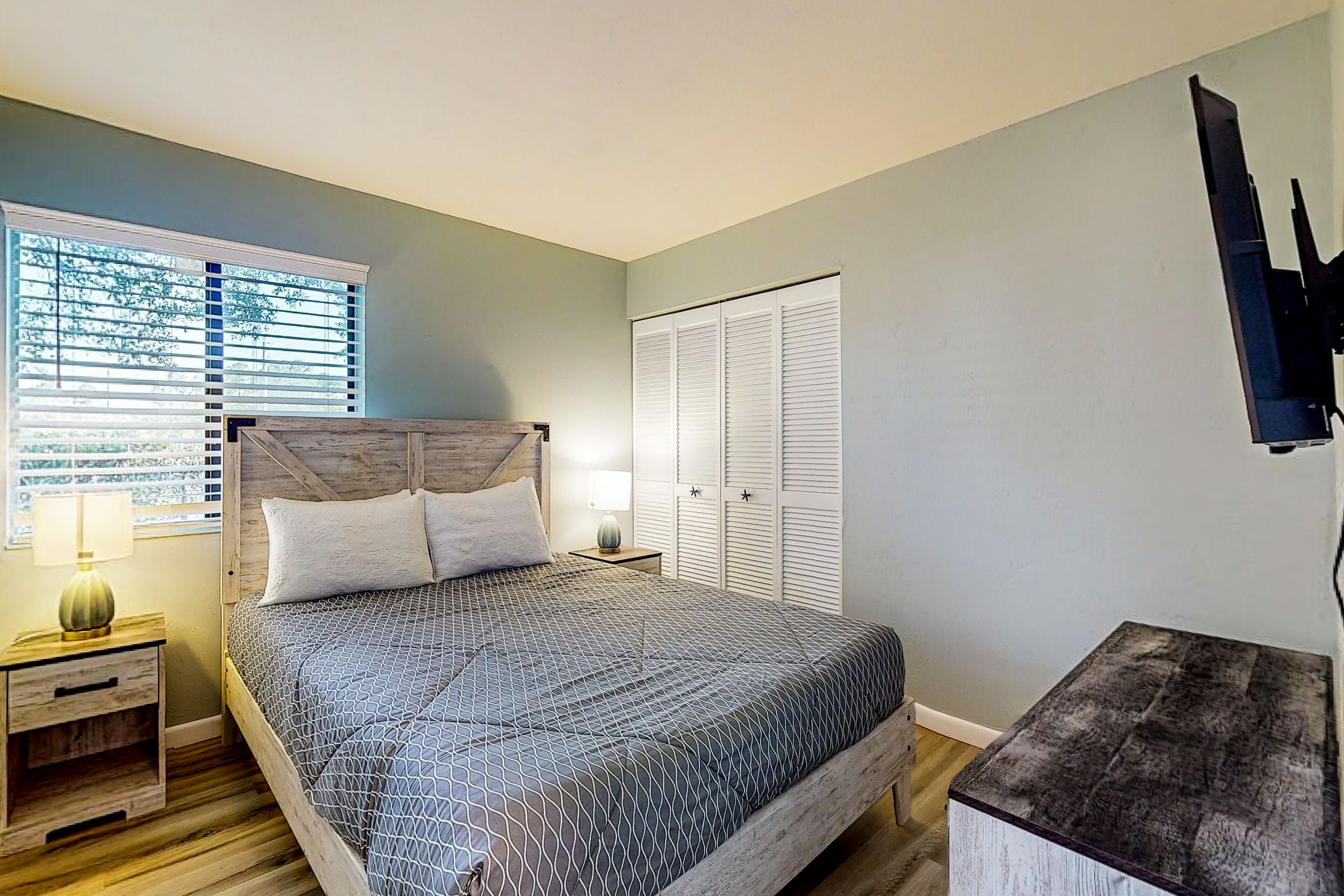 A bedroom with a bed, nightstands, a TV, and a closet.