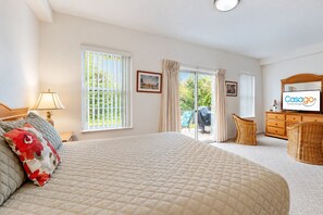 Une chambre d’hôtel avec un grand lit, une télévision, un bureau et une vue sur l’extérieur grâce à une porte coulissante.