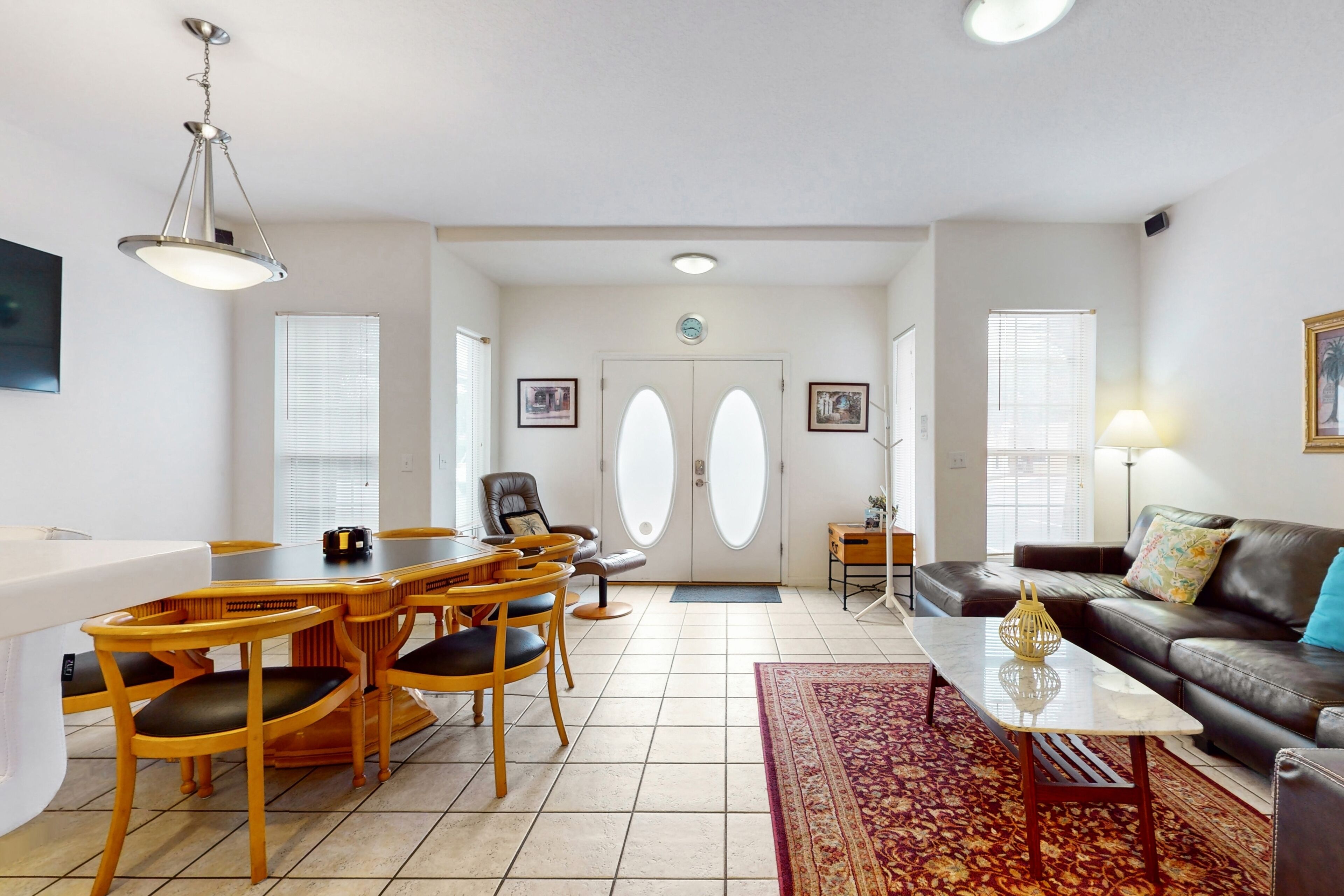 A spacious living area with a dining table, chairs, a sofa, and a coffee table.