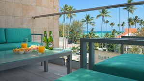 Ein Balkon mit Glastisch, zwei grüne Flaschen, ein Glas Orangensaft und eine Schale mit Snacks.