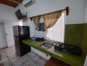 Eenvoudige bungalow | Privékeuken | Een koelkast met diepvriezer, een kookplaat, kookgerei, borden en bestek