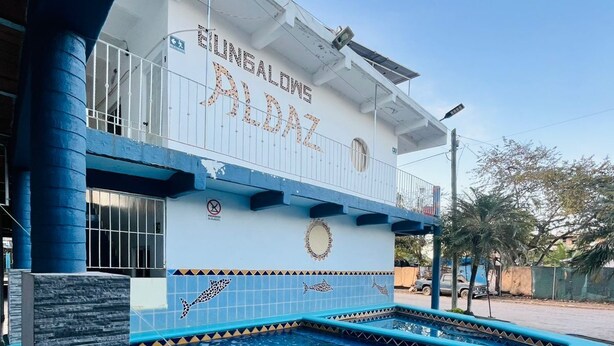 A building with a swimming pool, a balcony, and a sign that reads "BUNGALONG ALDOZ".