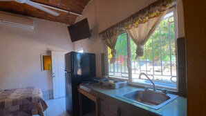 A compact kitchen with a refrigerator, a gas stove, and a sink.
