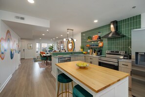 A modern kitchen with green tiles, stainless steel appliances, and a wooden island. - Funky Town - Walkable to Nashville Attractions (Nashville)