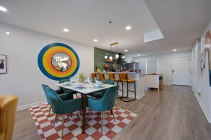 A modern kitchen with a green backsplash, a bar area with orange chairs, and a dining area with teal chairs. - Funky Town - Walkable to Nashville Attractions (Nashville)