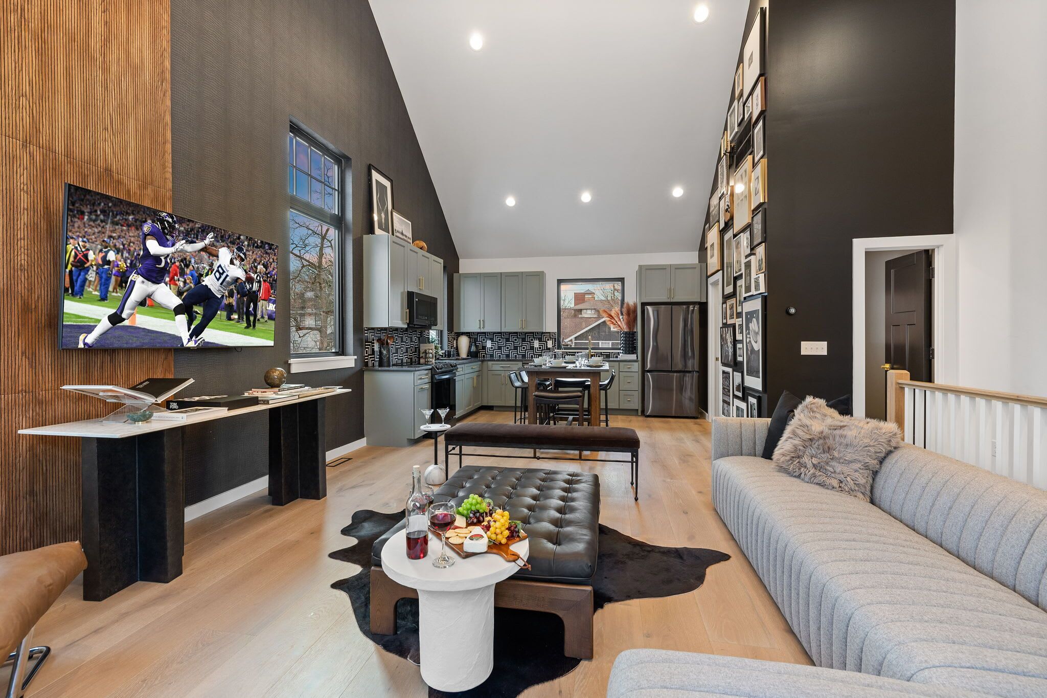 A modern living room with a flat-screen TV, a dining area, and a kitchen.