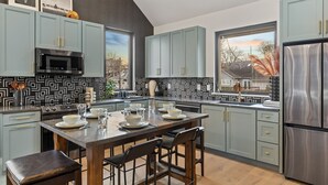 Une cuisine moderne avec des meubles de couleur bleu clair, un réfrigérateur en acier inoxydable et un coin repas comprenant une table et des chaises en bois.