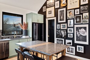 Una cucina moderna con un'ampia finestra, un'area pranzo con tavolo in marmo e una parete decorata con quadri.
