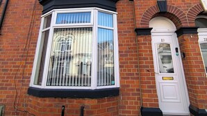 A red brick building with a bay window and a white door.