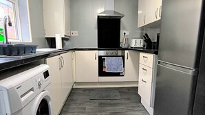 A compact kitchen with a washing machine, a built-in oven, a toaster, and a refrigerator.