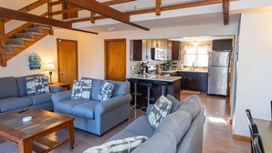 Una sala de estar con escalera, una cocina con electrodomésticos modernos y una zona de bar.