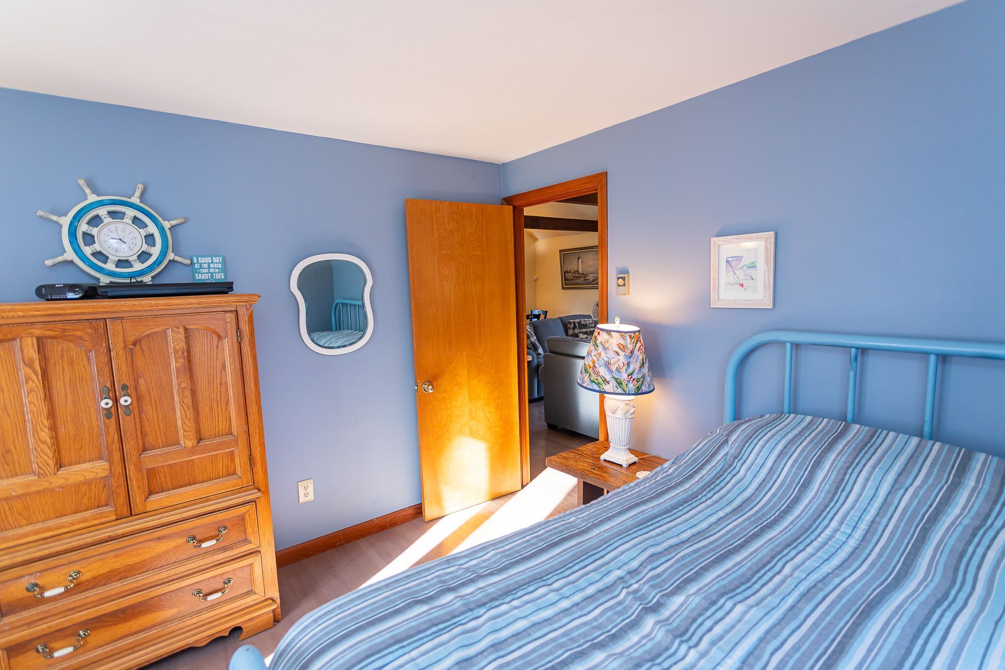 A bedroom with a bed, wooden wardrobe, and a door leading to another room.