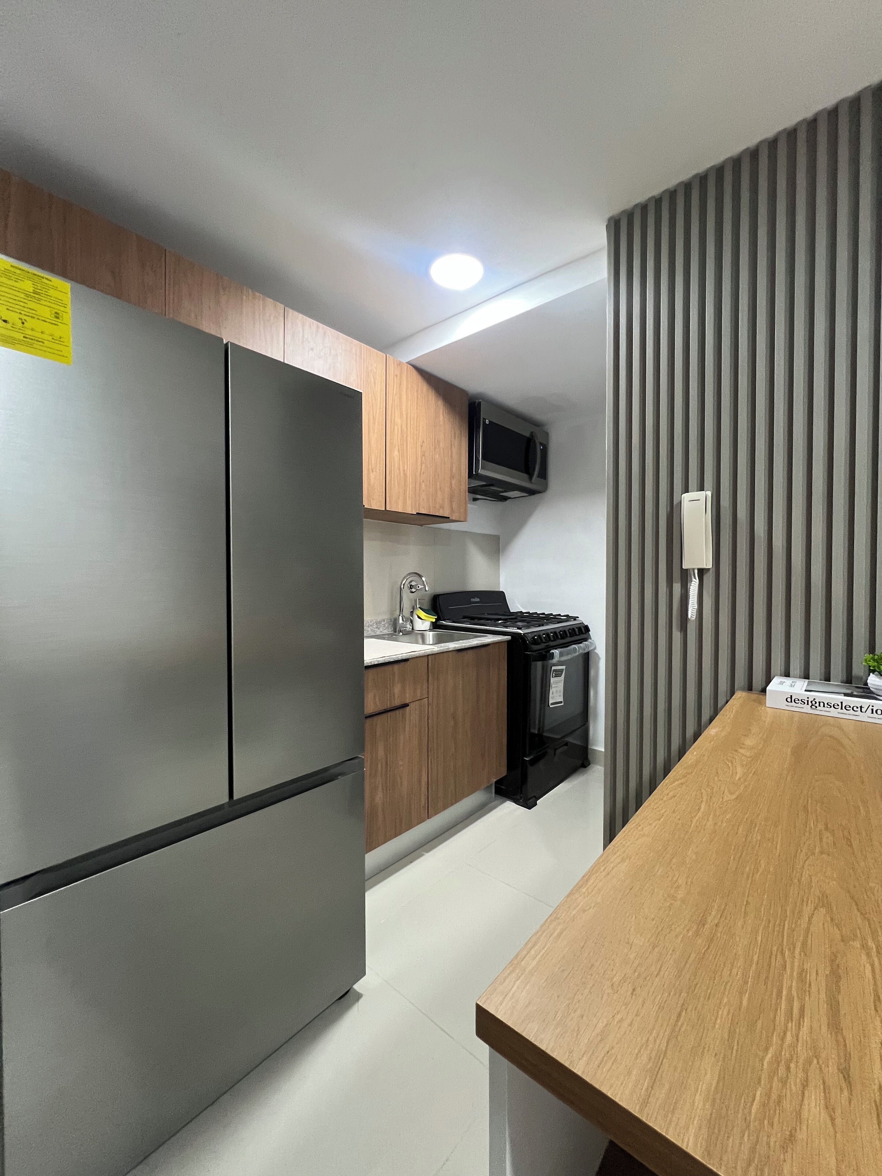 A modern kitchen with stainless steel appliances, wooden cabinets, and a built-in microwave.