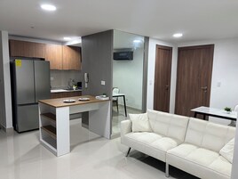 Una cocina moderna con refrigerador empotrado, encimera de madera y sofá blanco en la zona de estar.