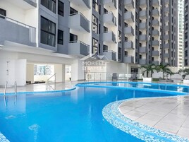 A modern indoor swimming pool with a tiled edge, surrounded by a multi-story building with balconies and a sign reading "MORELL & FAMILY".