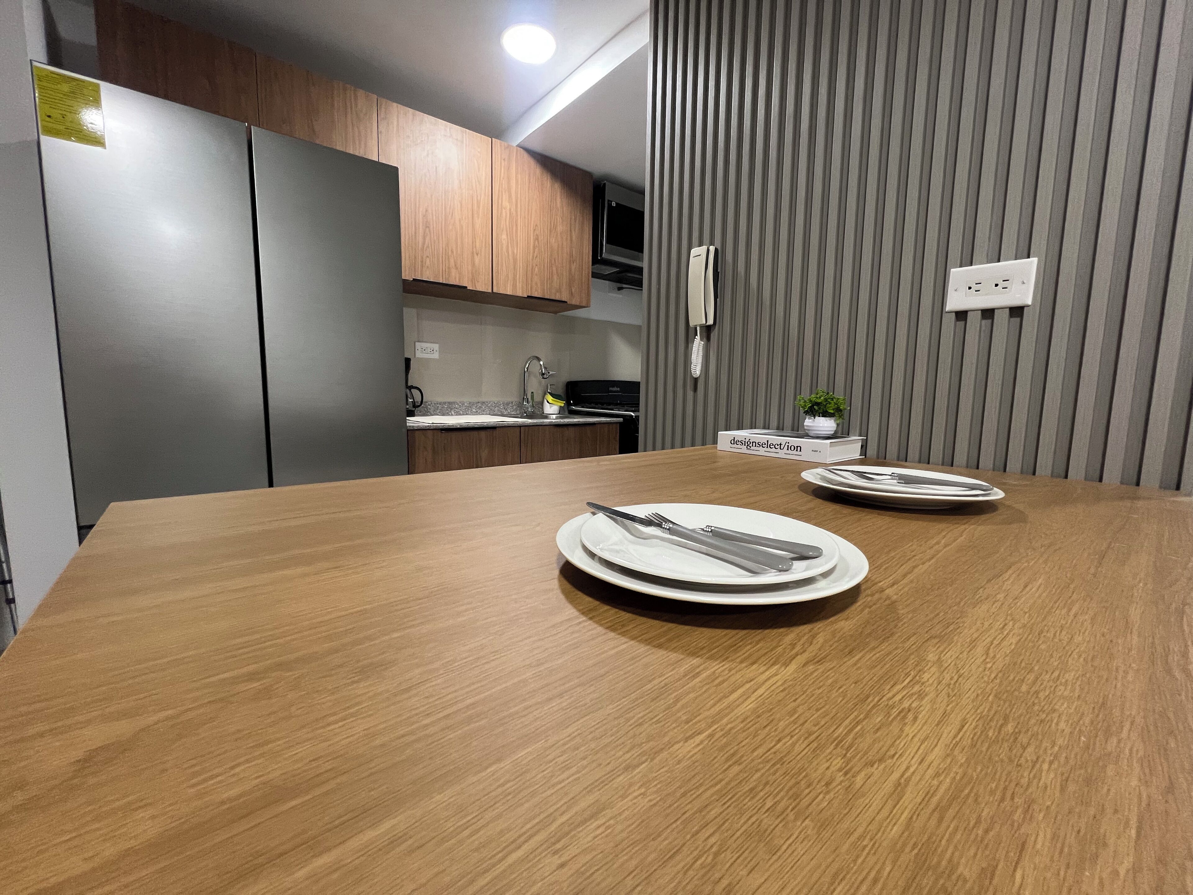 Una cocina moderna con armarios de madera, horno empotrado y refrigerador gris.