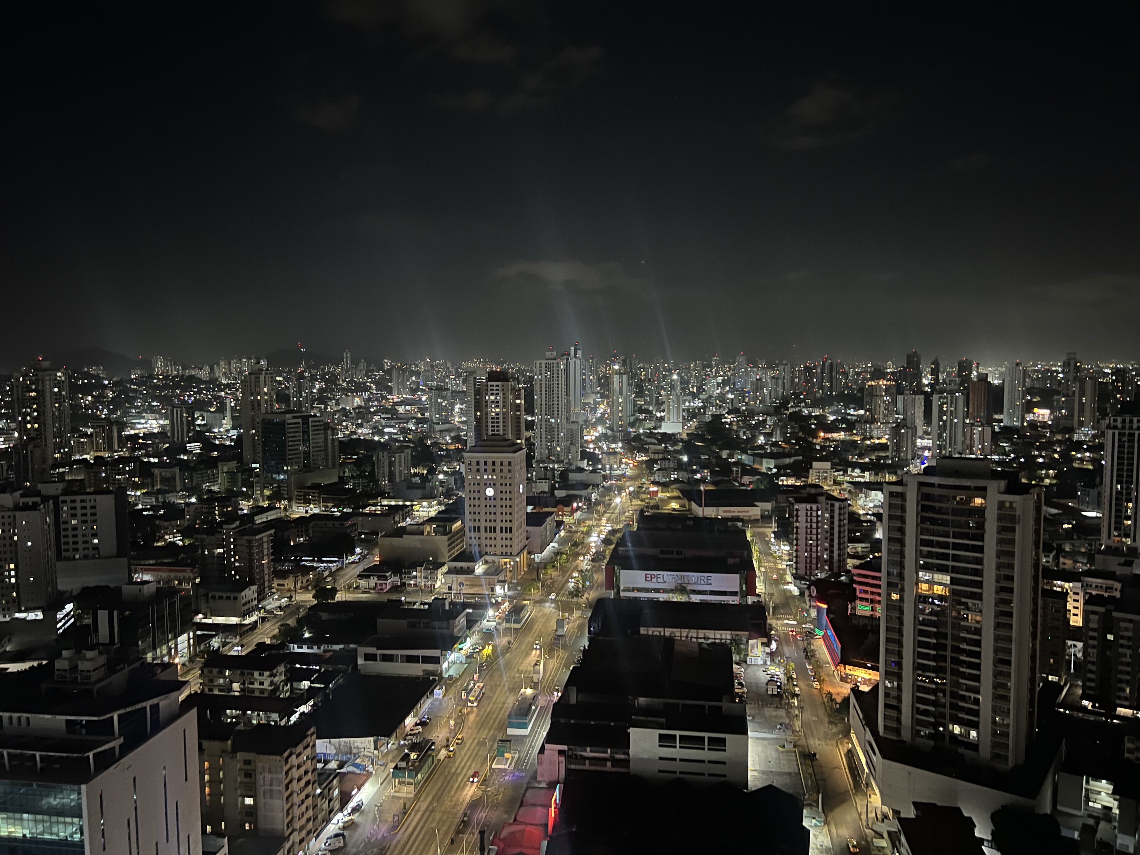 A nighttime cityscape with a view of a busy street and tall buildings.