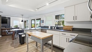 A modern kitchen with white cabinets, a wooden countertop, and a built-in oven. - Tampa Oasis: Pool & Hot Tub Retreat for Families (Tampa)