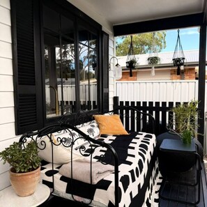 A balcony with a bed, a small table, and potted plants. - Peaceful Nelson Bay Retreat with Boutique Flair (Nelson Bay)