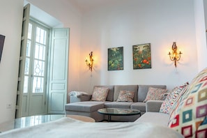 A modern living room with a sofa, a coffee table, and two wall-mounted lamps.