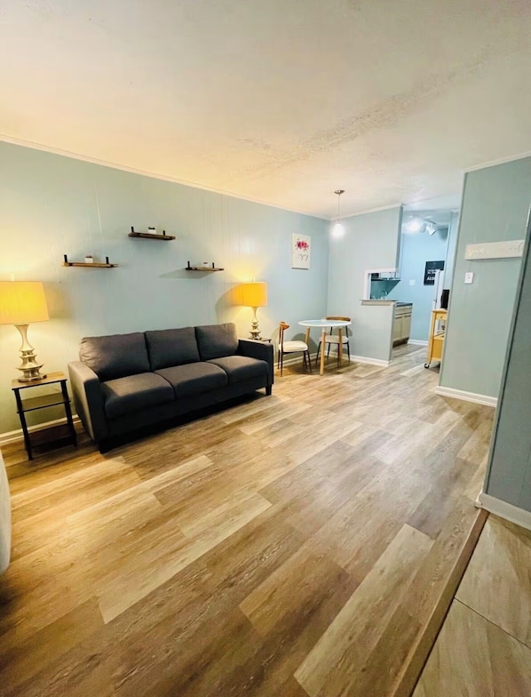 Ein Wohnzimmer mit einer Couch, zwei Lampen, einem Couchtisch und einer kleinen Essecke mit Tisch und Stühlen.