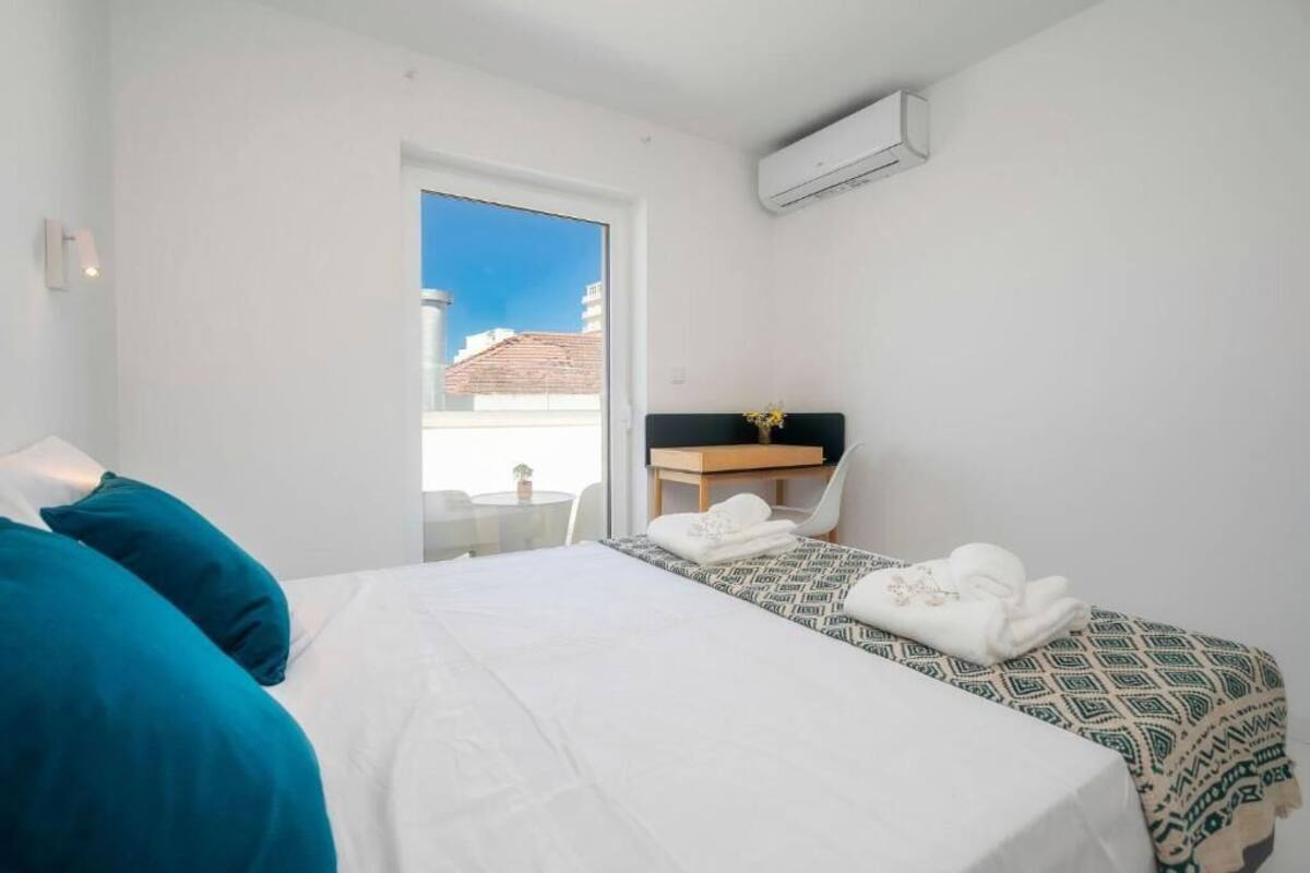 A hotel room with a bed, a desk, and a window.