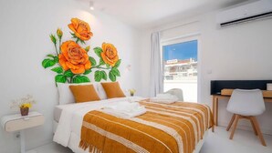 A modern hotel room with a large bed, a desk, and a window with a city view. - Primavera House - Sakura (Faro)