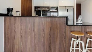 A modern kitchen with wooden accents, stainless steel appliances, and a bar area with stools. - Magnificent Apartment in the Heart Nuevo Polanco (Mexico City)