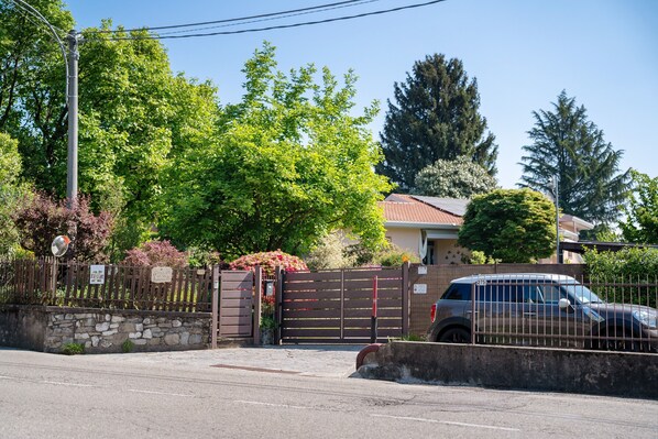 A gated residential area with a parked car, a stone wall, and a metal fence.